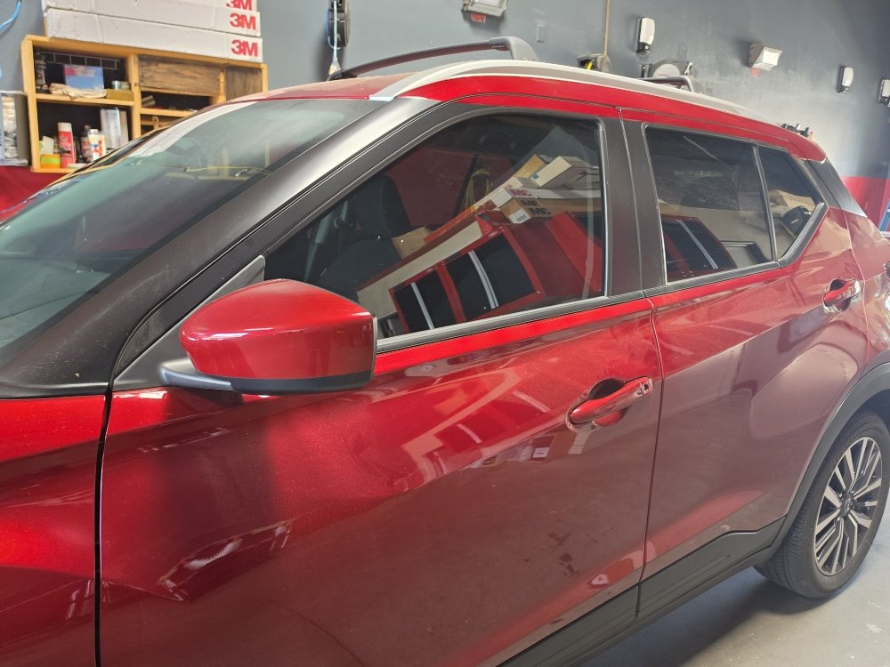 Red Nissan Kicks with fresh window tint in the shop