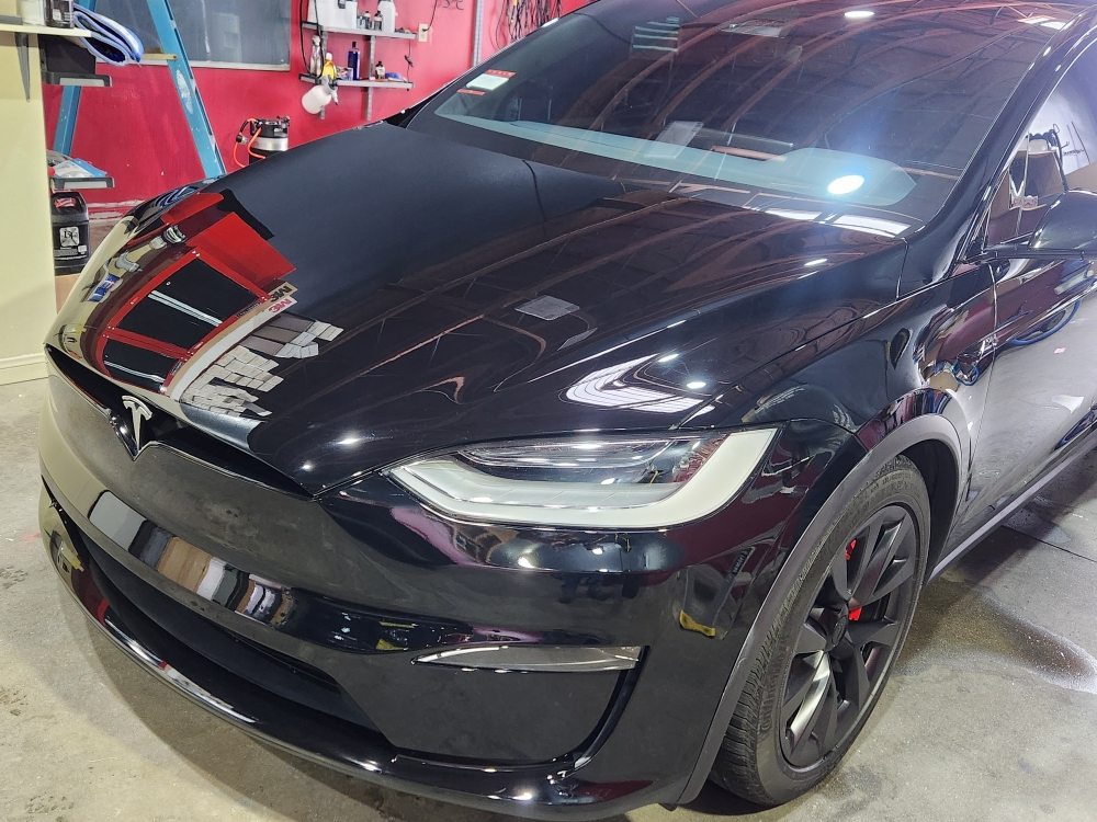Black Tesla Model X with a deep gloss finish in the shop